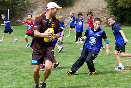 Hawthorn player Brad Sewell tries to keep the ball away from Hutchins Junior School students.