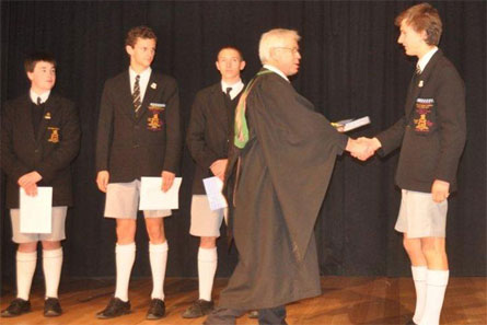 Henry West receives his Geography Competition Prize from Acting Headmaster Barrie Irons at the Headmaster's Assembly.