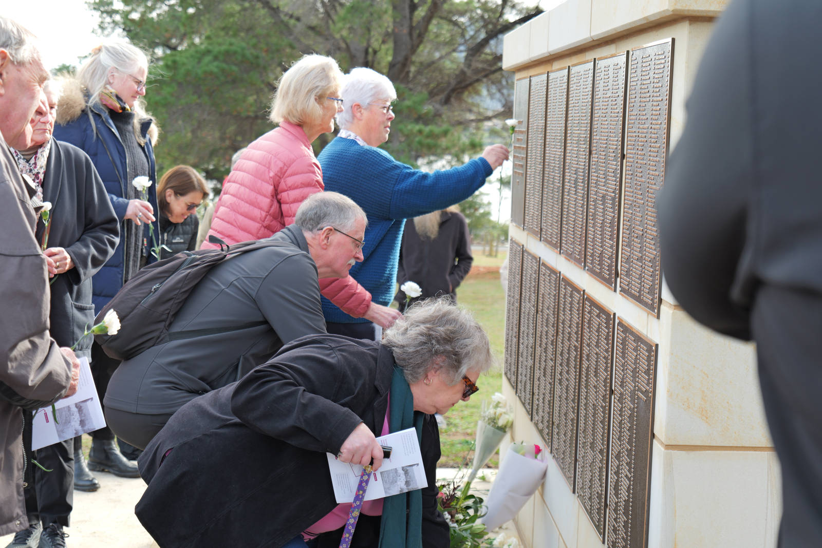 Guests placing white carnations at the new memorial at Cornelian Bay, The Hutchins School Reinterment Service, 11 June 2025